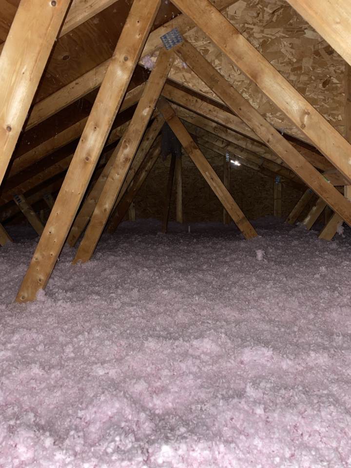 Attic with blown-in insulation covering the floor between rafters