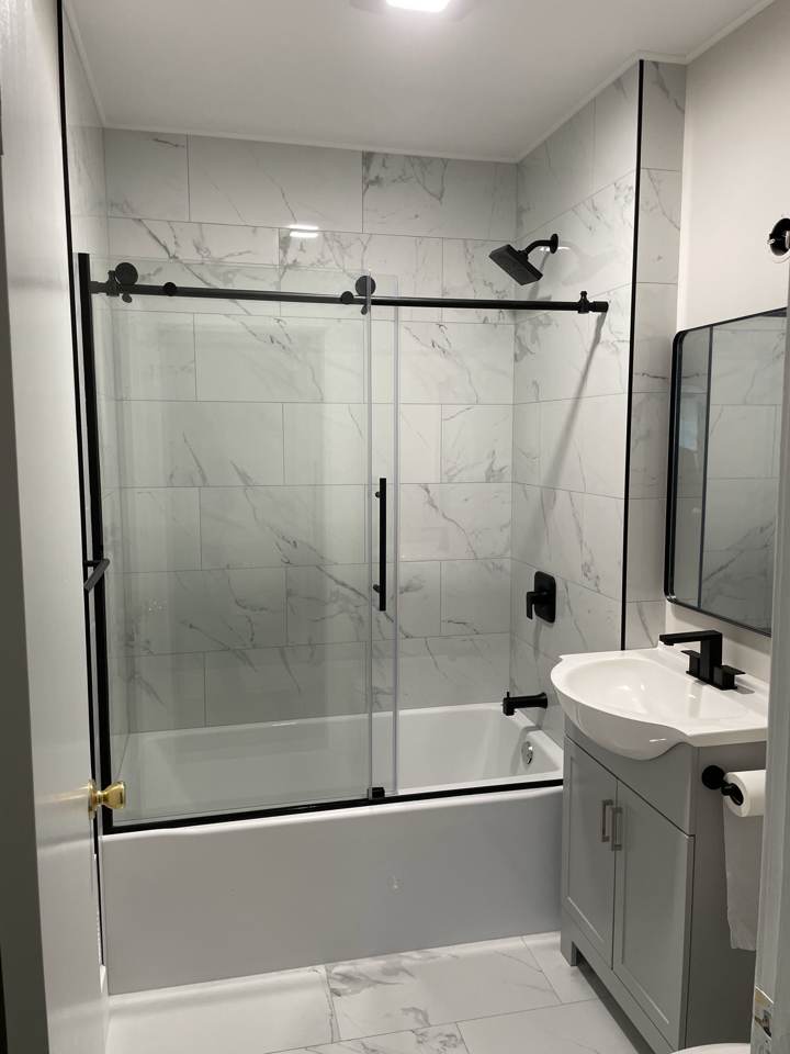 Bathroom with tub, glass sliding door, and marble-look tile