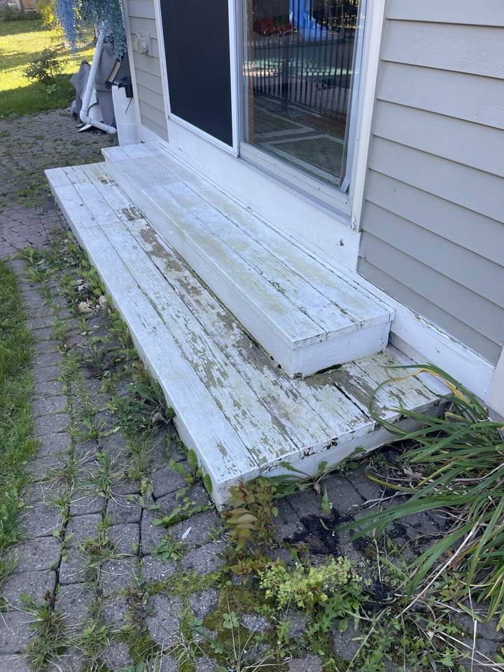 Old rotted deck steps at a sliding door before replacement