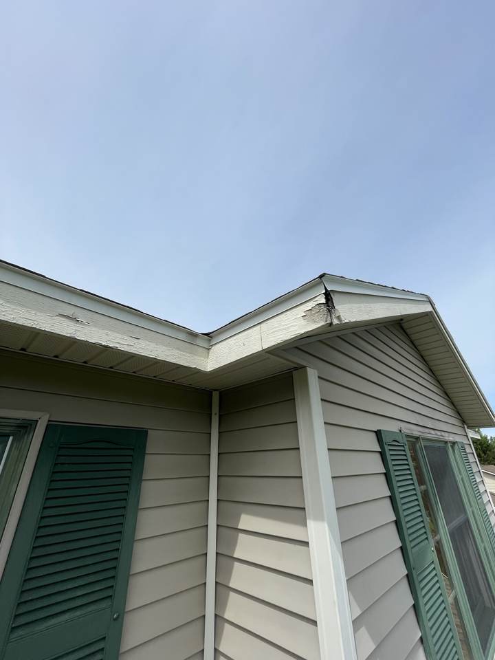 Damaged and split fascia at a roof valley corner before replacement