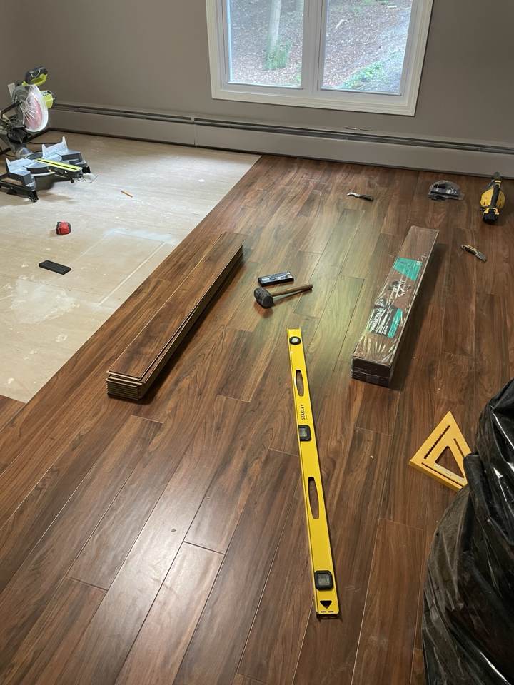 Hardwood flooring being installed with level and tools