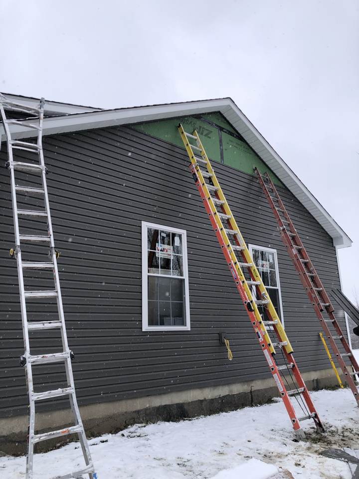 New dark gray siding installed on a house with ladders