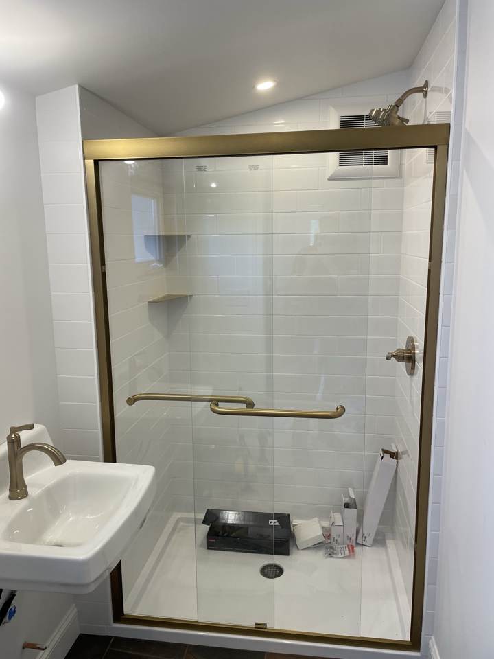 Walk-in shower with glass door and brushed gold fixtures