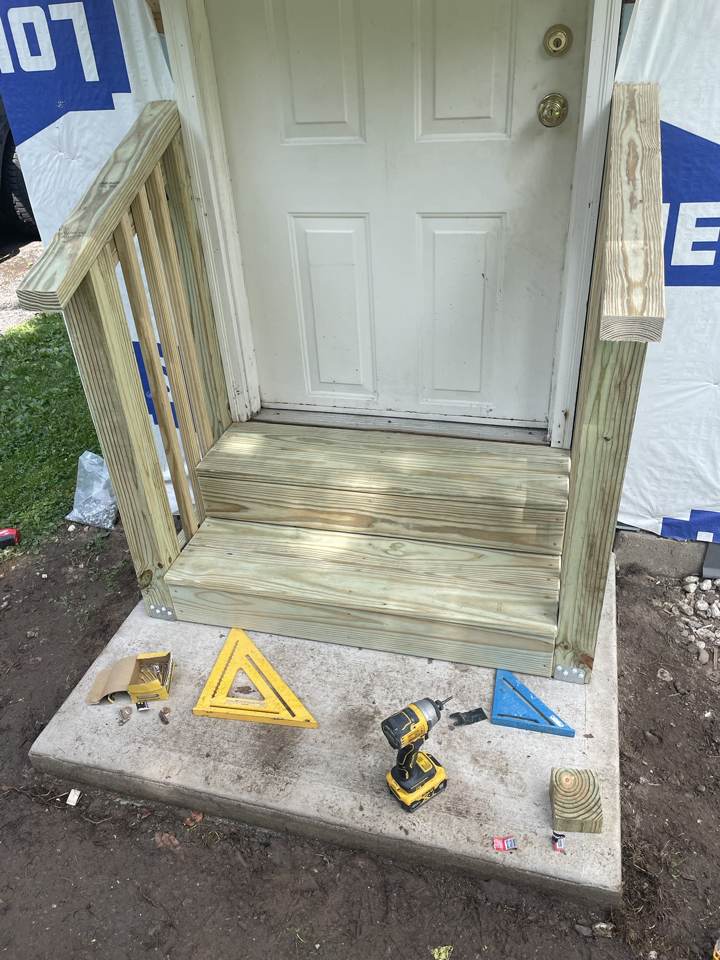 New treated-wood entry steps with railings at a door